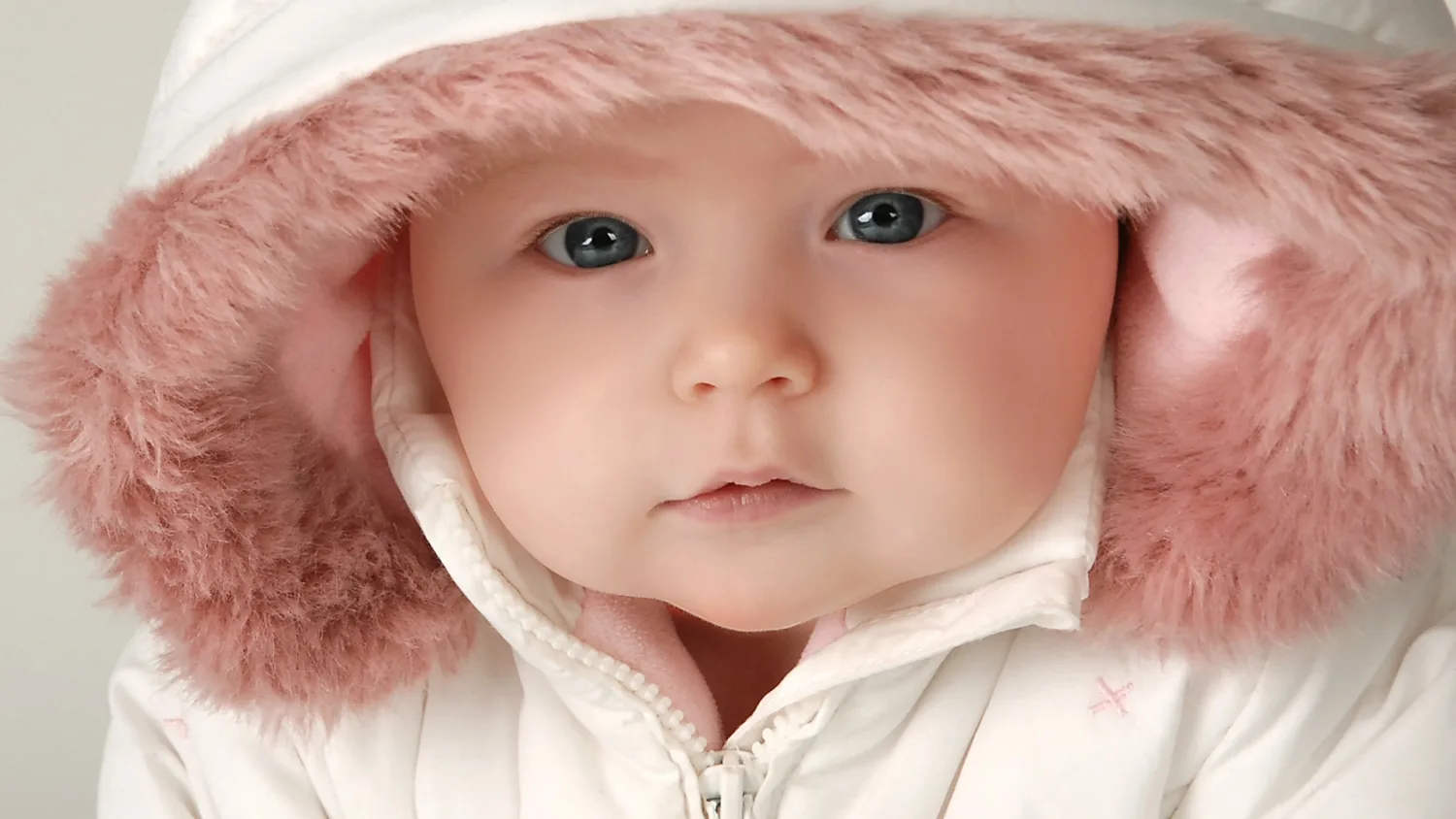Baby mit rosa Fellkapuze schaut in die Kamera