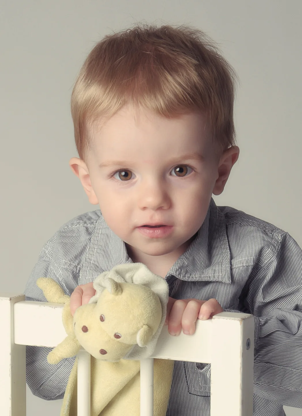 Kleiner Junge im grauen Hemd mit Kuscheltier